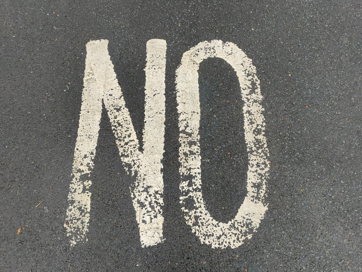 The word "NO" painted in large white letters on worn tarmac